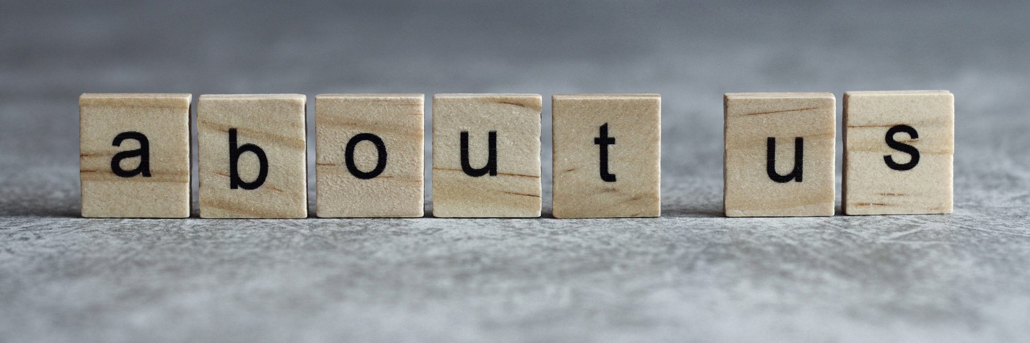 Über uns Wort geschrieben auf Holzwürfel mit grauem Hintergrund.