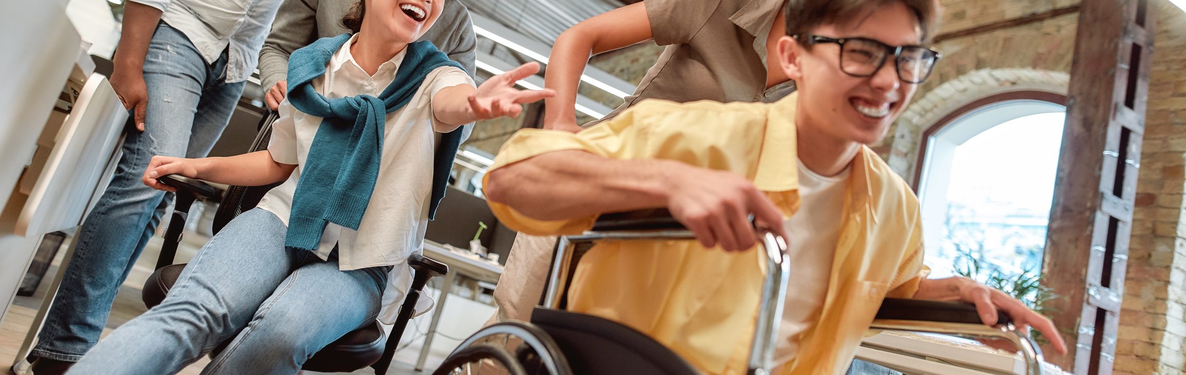 Positiv bleiben. Junge glückliche asiatische Mann im Rollstuhl Spaß mit seinen Kollegen im modernen Büro – Stockfoto